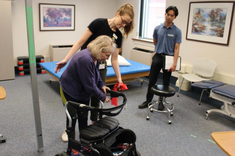 a student helping an elderly person to use their walker