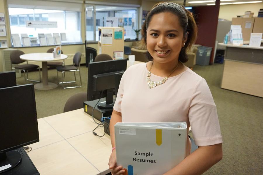 a woman holding a binder and smiling at the camera