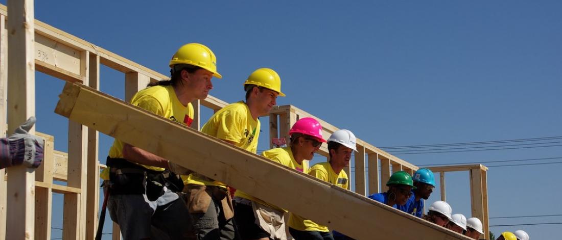 Group of faculty and staff lifting a heavy beam.