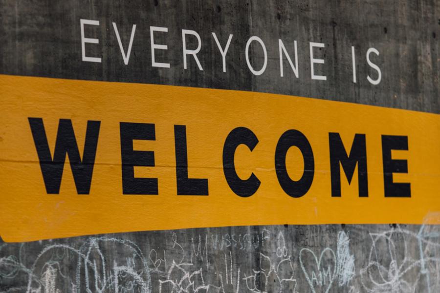 A concrete slab with the words everyone is welcome written on them and below some street graffiti art.
