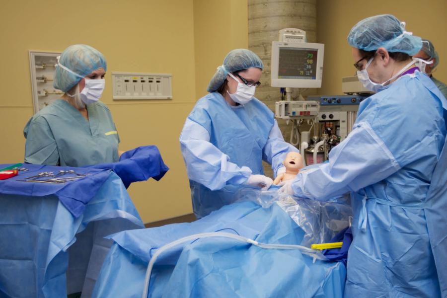 Four medicine students practice in a simulation lab.