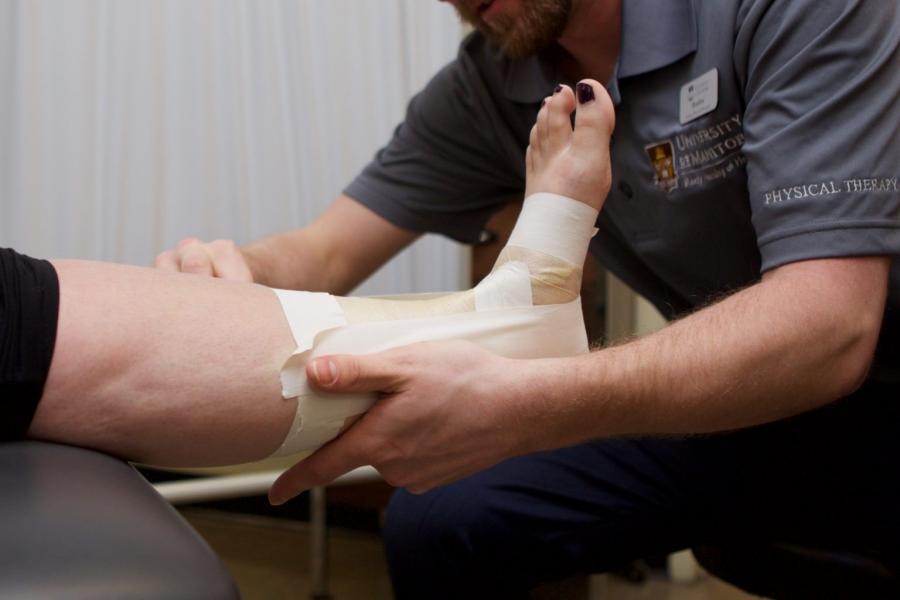 Physical therapist works on a bandaged leg.