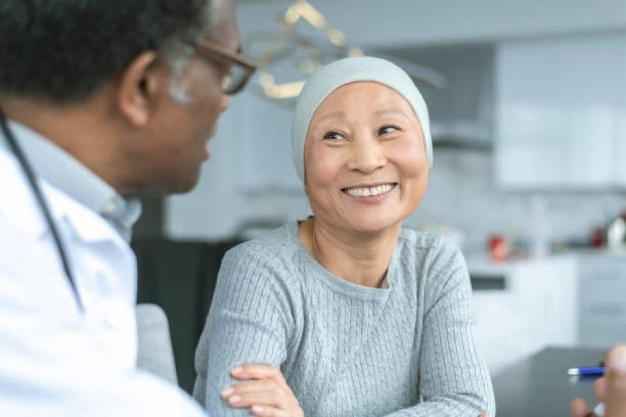 Smiling patient wearing a head scarf talks to her physician.