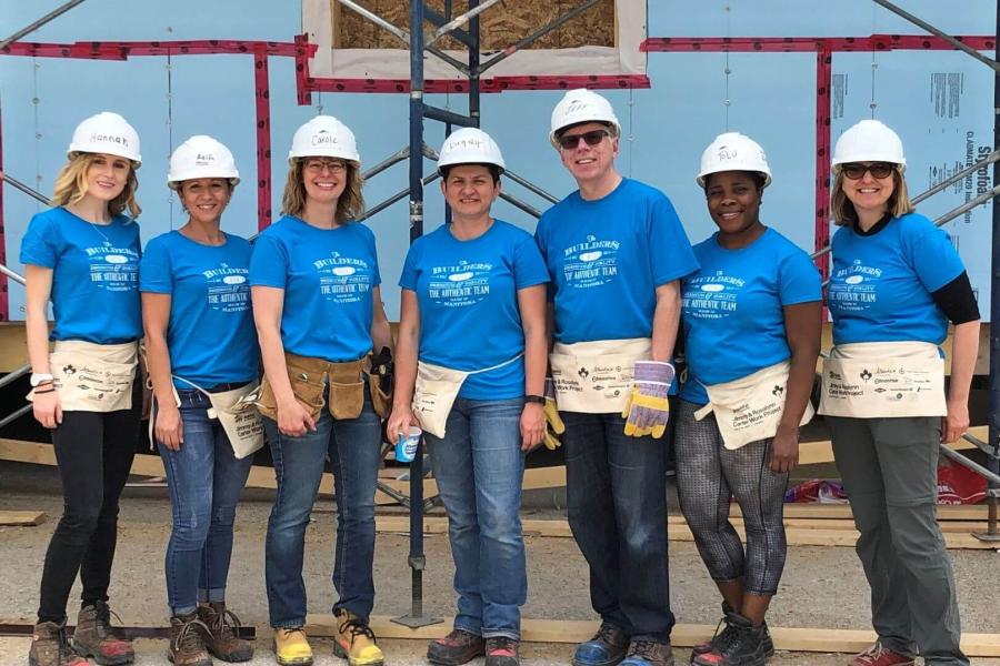 Staff wearing blue Habitat for Humanity t-shirts in front of a construction site.