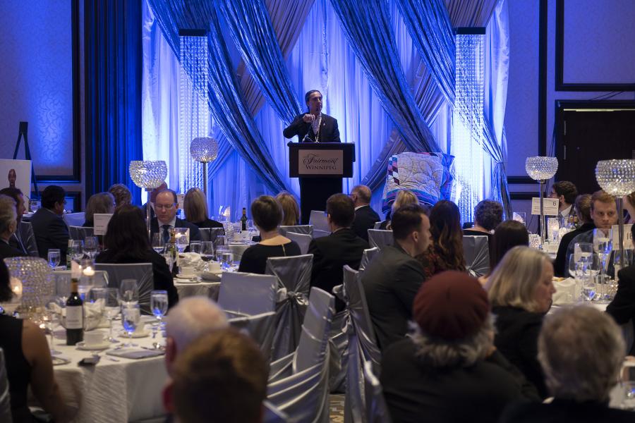 Speaker at a podium at a dinner event.
