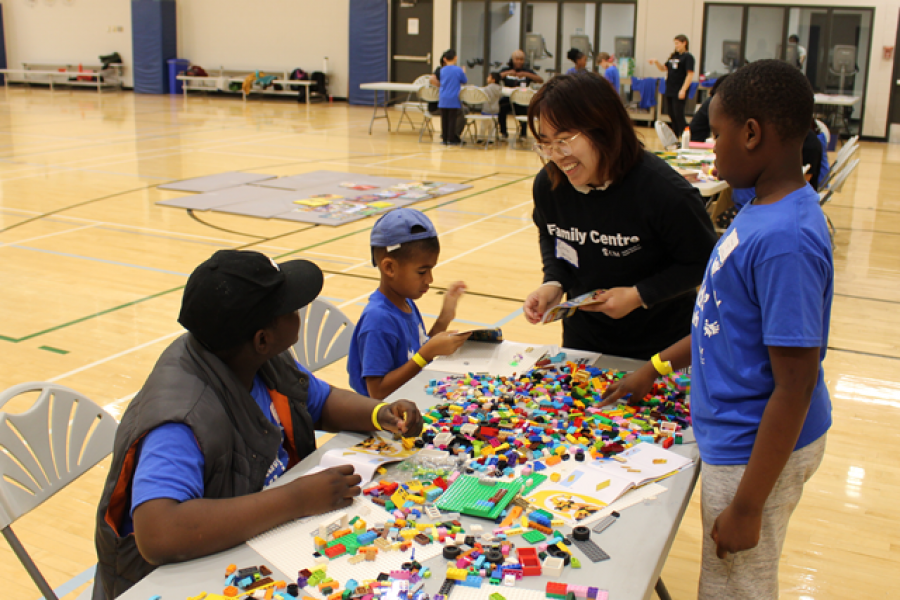A  child minder is building Lego with children attending Rady Kids' Club.