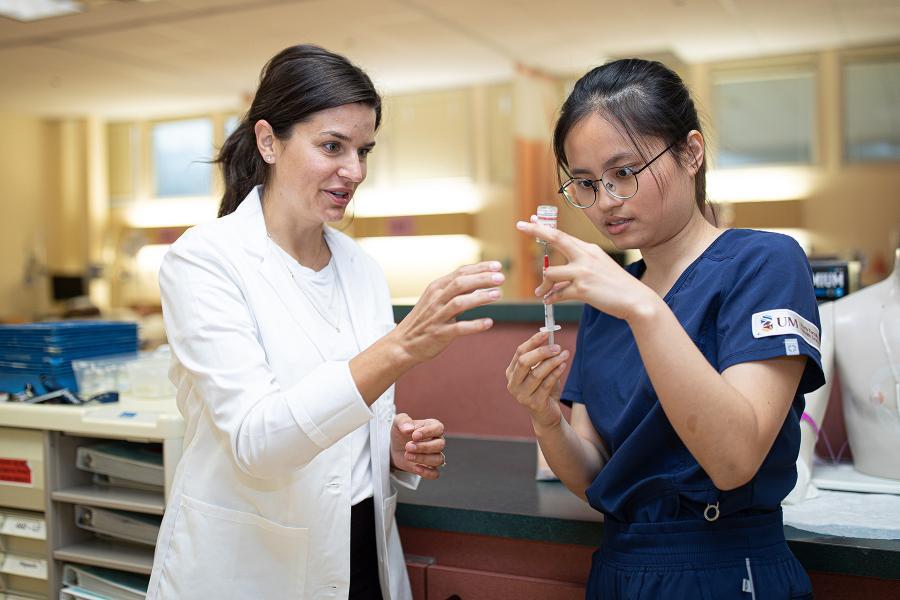 Nurse teaches a trainee to fill a syringe.