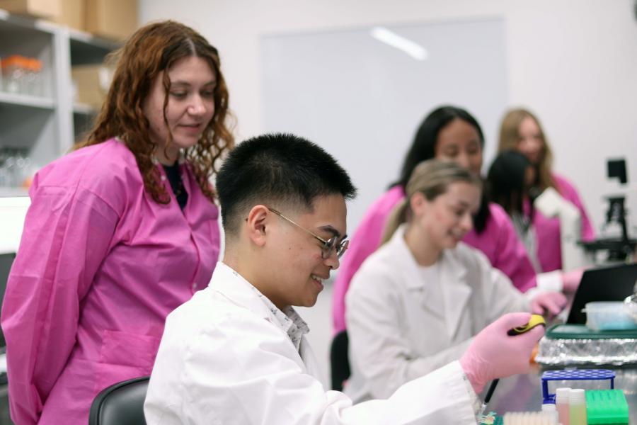 A researcher and students in a lab.