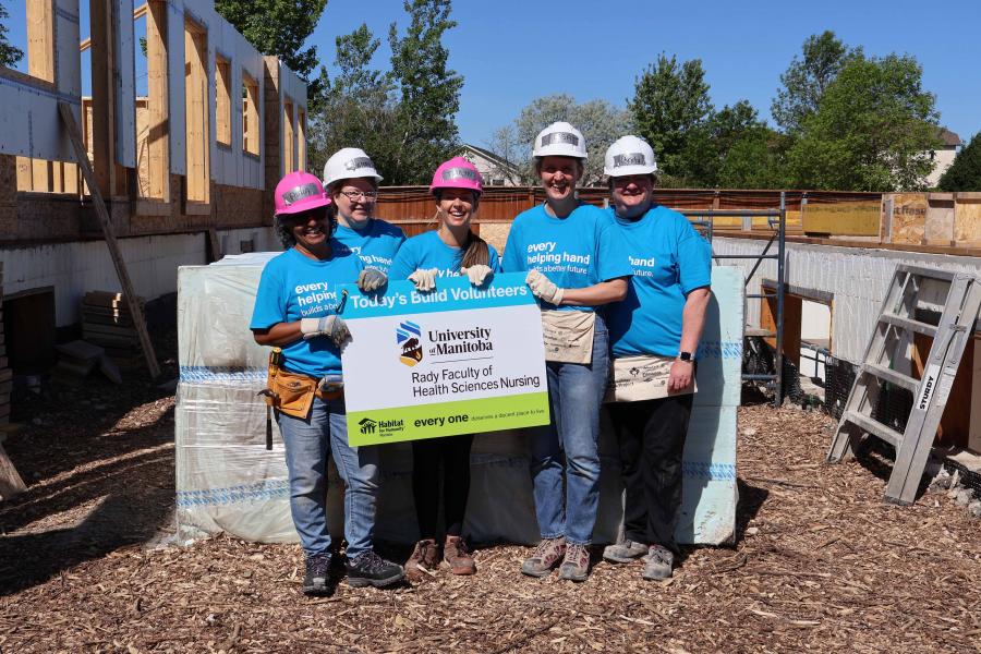Staff wearing blue Habitat for Humanity t-shirts in front of a construction site.