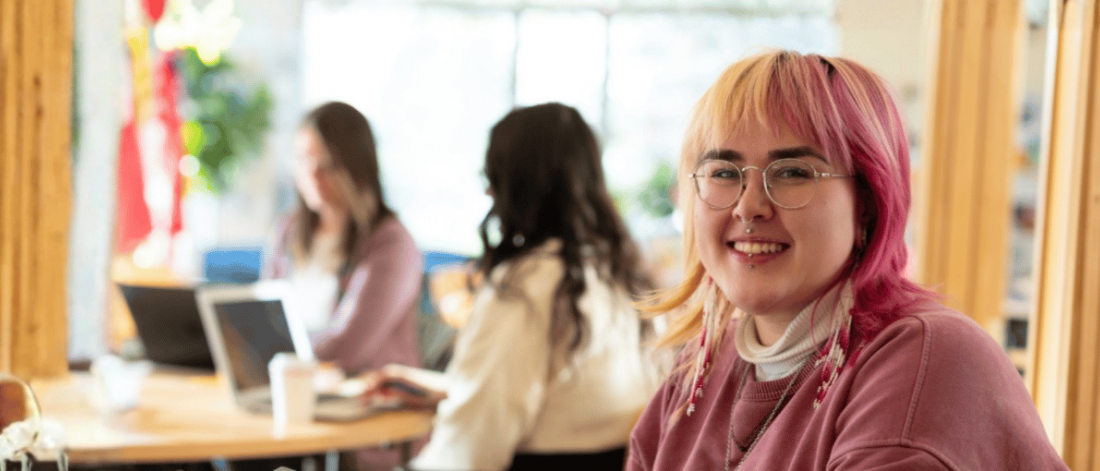 Smiling student studying in a bright campus space.