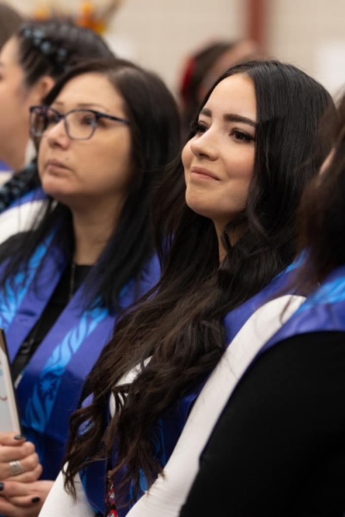 Indigenous graduates wearing blue stoles at a graduation pow wow