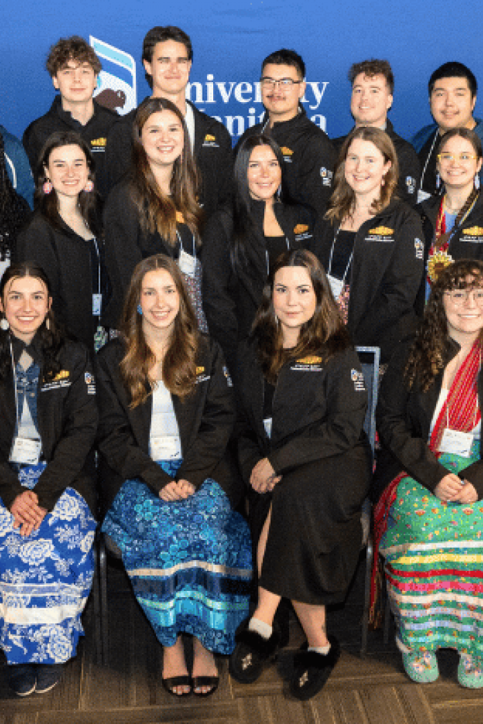 Group photo of University of Manitoba Indigenous leadership program participants and staff at a campus event, standing and seated in front of program banners.