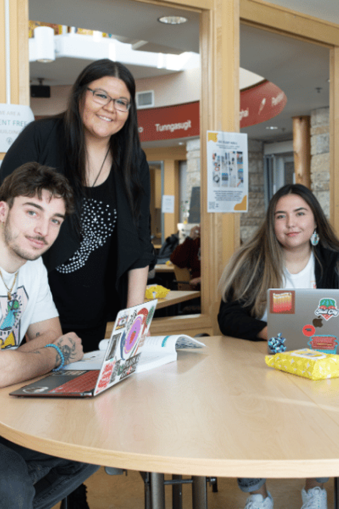 Four students gathered around a table in a campus study space.