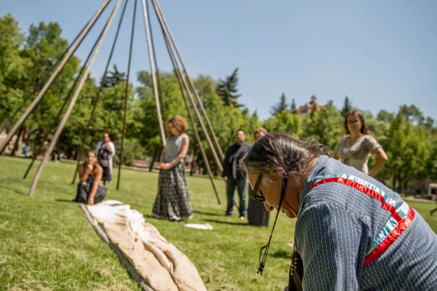 Carl Stone and several others work on constructing a teepee at the Fort Garry campus.
