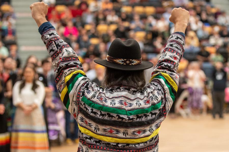 view from behind elder cheering on graduates with arms in the air