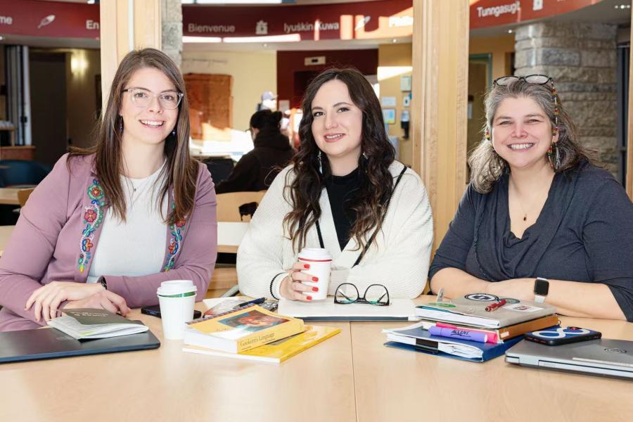 Three students sit together at a table during a study session in an Indigenous student space.