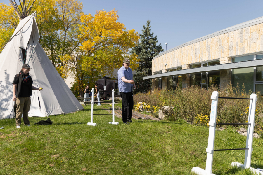 Students playing ladder toss beside a tipi during Orientation.