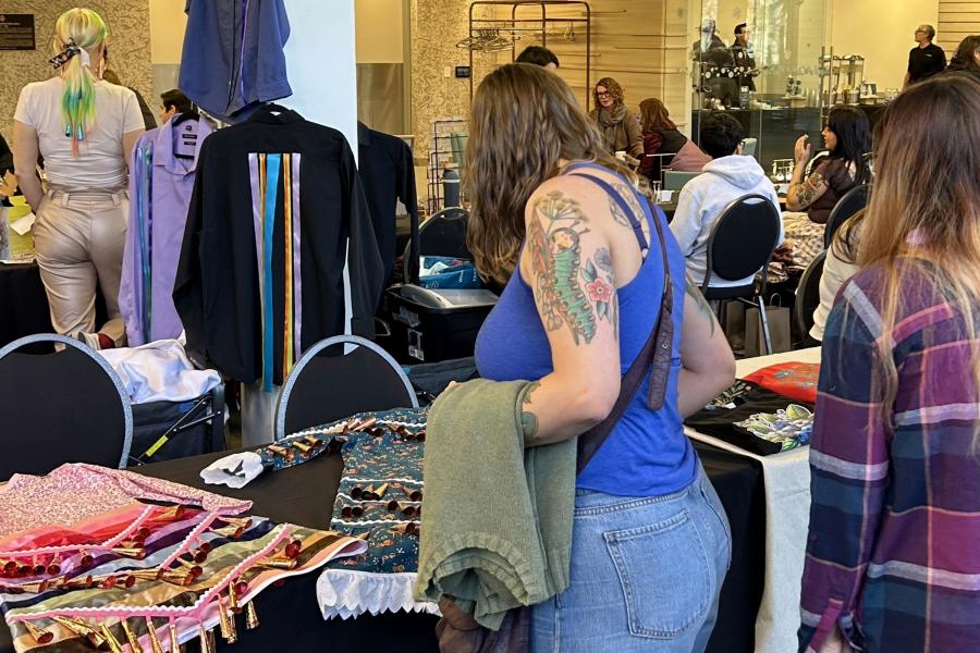 Attendees browse Indigenous-made items and artwork at vendor tables during an Indigenous market event held indoors on campus.