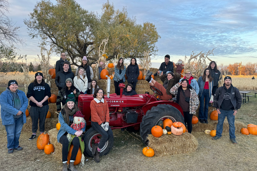 Students pose with pumpkins and a vintage tractor.