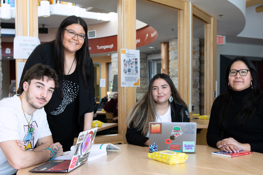 Two students smile and look at a laptop together.