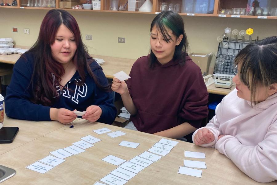 Three students sitting at a table doing an activity.