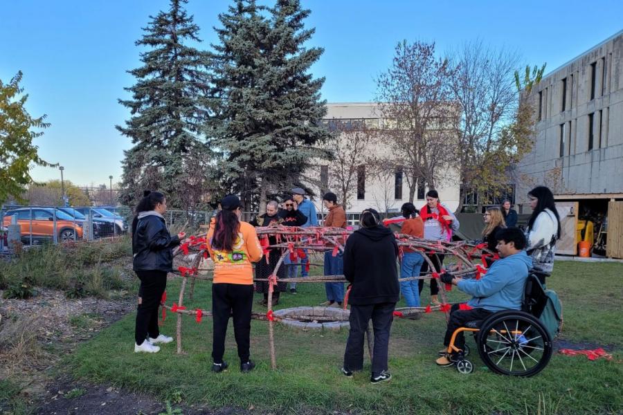 A group of people working together outdoors to re-build the sweat lodge on campus.
