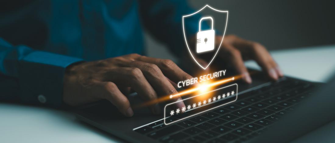 Hands at a laptop keyboard with cybersecurity hovering over the laptop