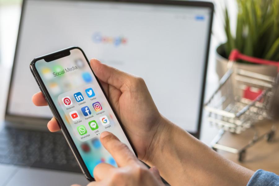 Person holding an iPhone with social media apps on the screen.