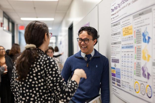 Two people talking and laughing in front of an informational poster