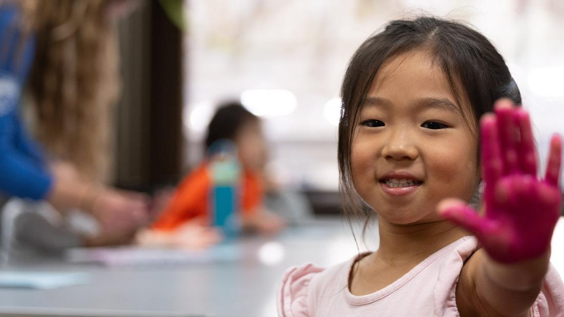 A girl smiling holding her painted hand up in front of her