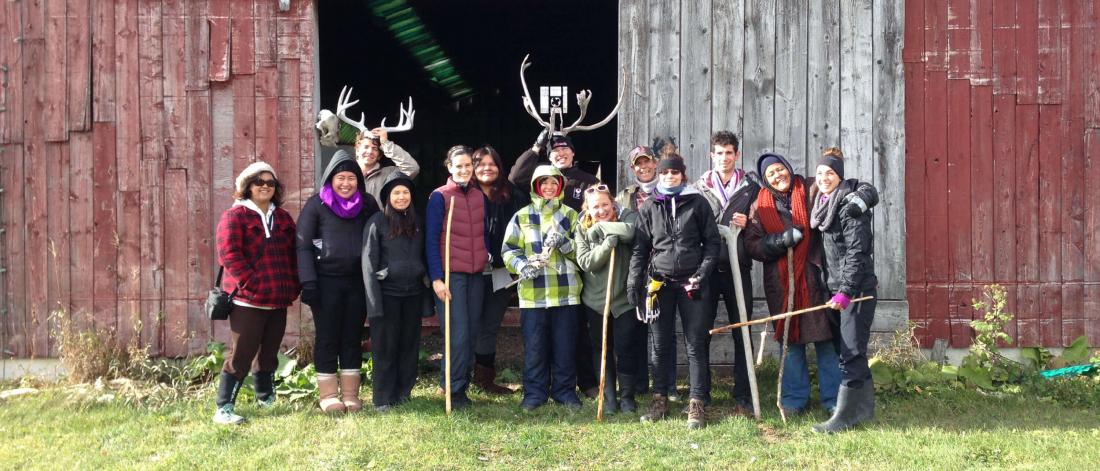A group of people stand together in front of a barn. 