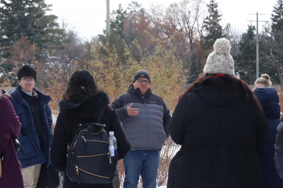Dr. Dan Henhawk during an outdoor class speaking with students during the winter