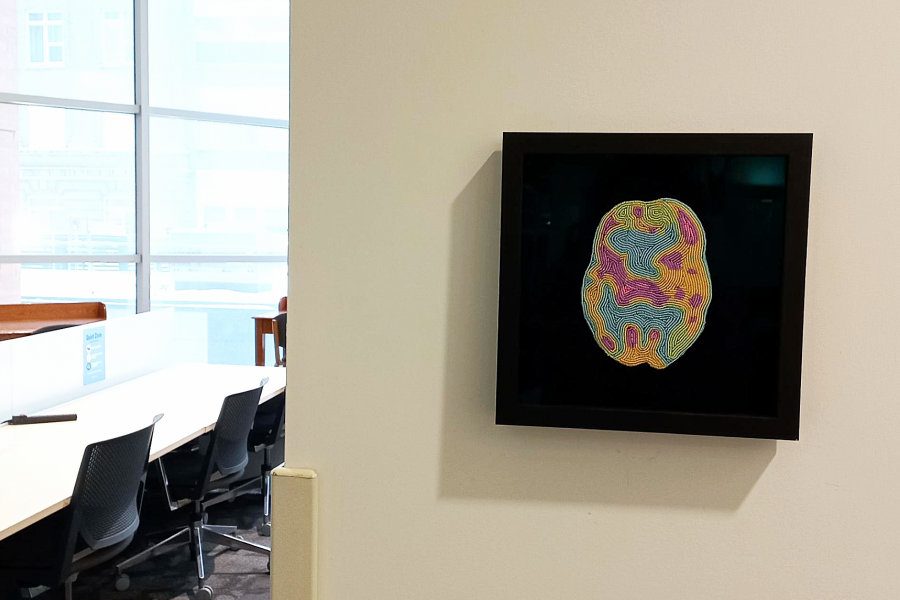 A beaded brain scan framed on a wall