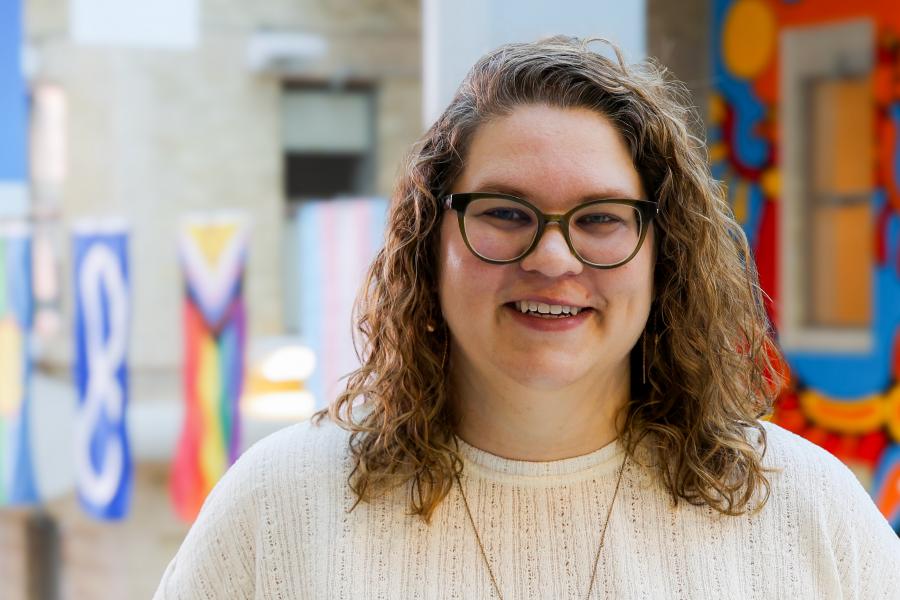 Dr. Amy Freier standing in front of the Brodie atrium, smiling, with flags hanging down from the vaulted ceiling behind her.