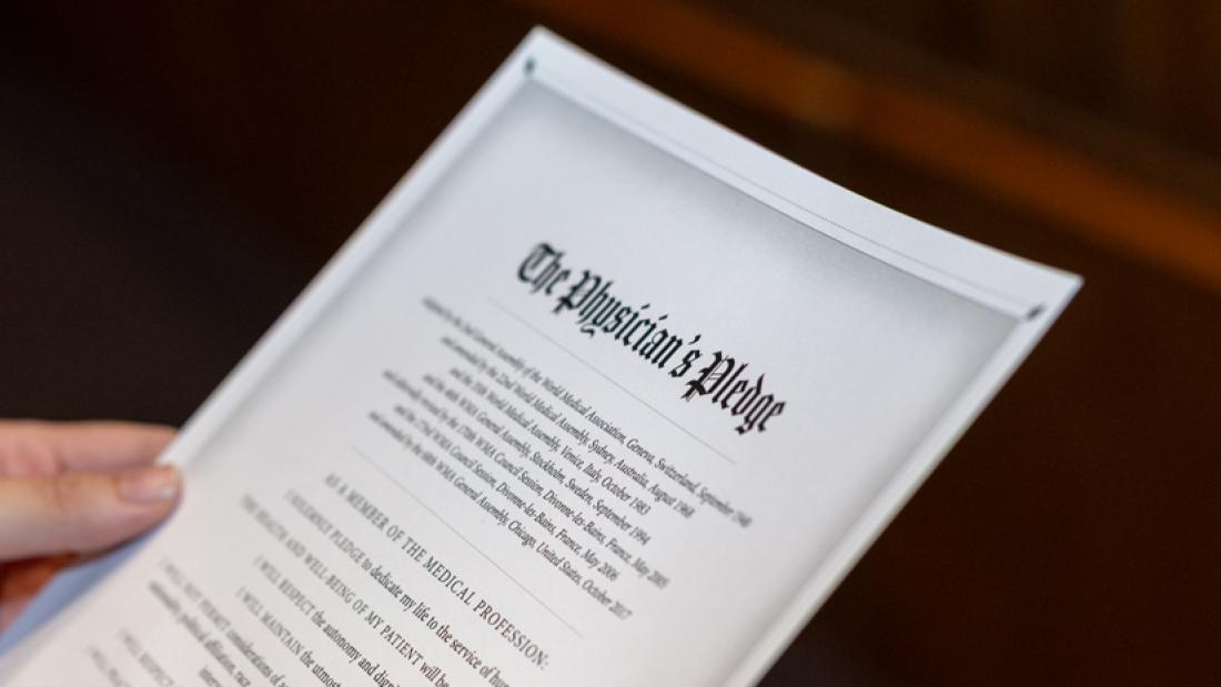 A close up of a person holding the physicians pledge