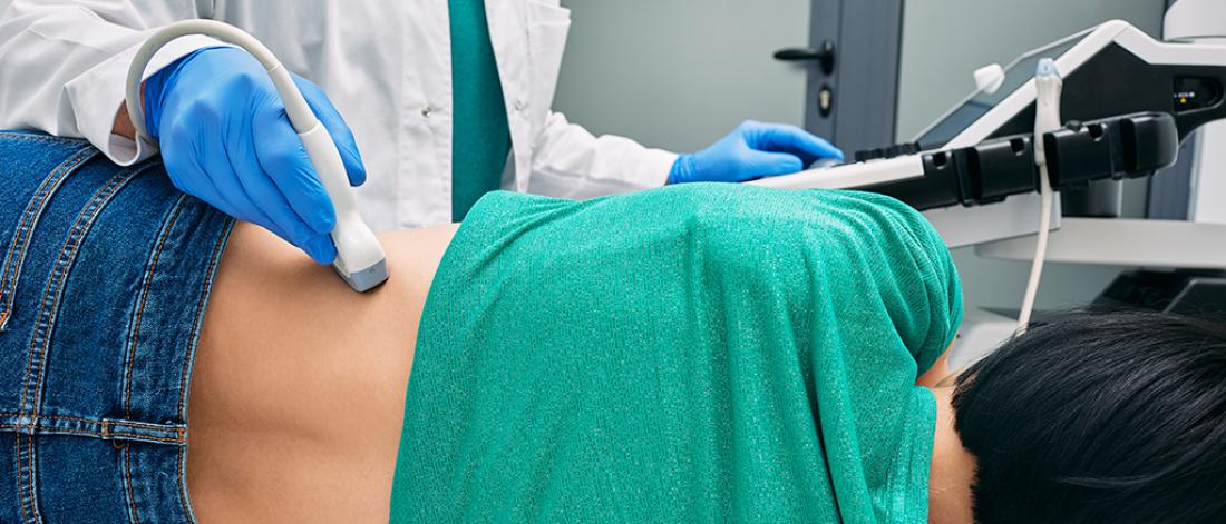 Ultrasound of kidneys. Woman patient during ultrasound examination in medical clinic lying on side, view from back
