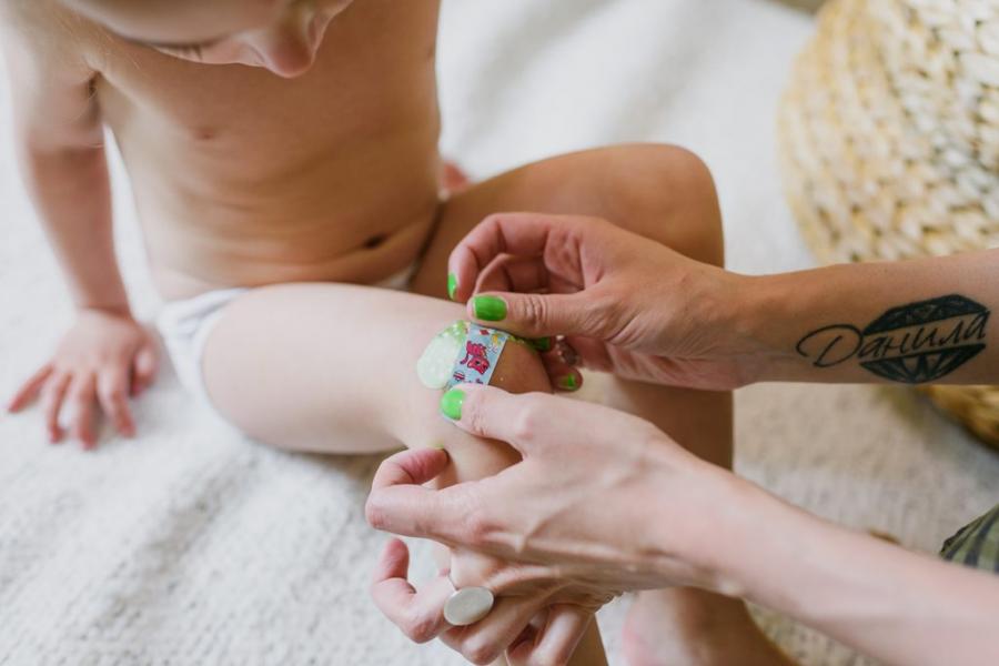 Mother puts a bandaid on her child's knee.