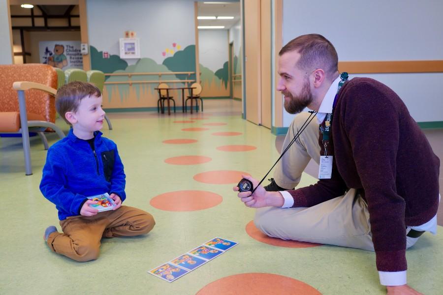 A Psychologist sits on the floor of a clinic with a child.