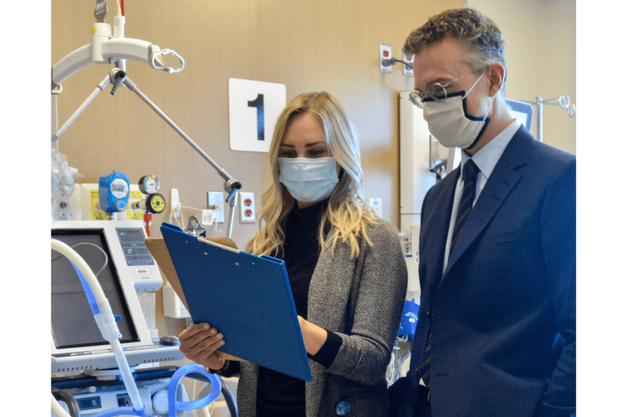 Two doctors stand side by side looking at a medical chart.