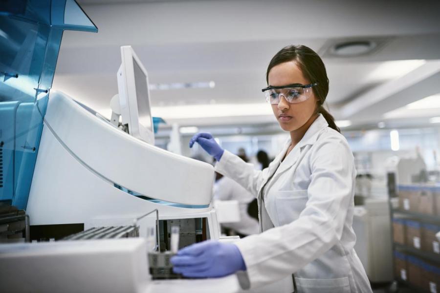 A lab technician in a white coat performs a lab task.