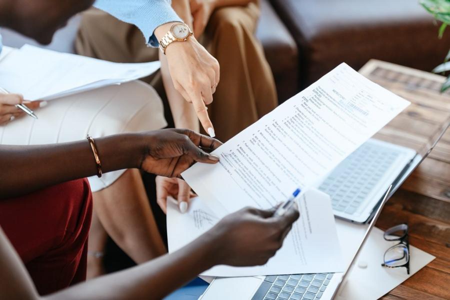 A person holding a document that is being reviewed by a group of people.