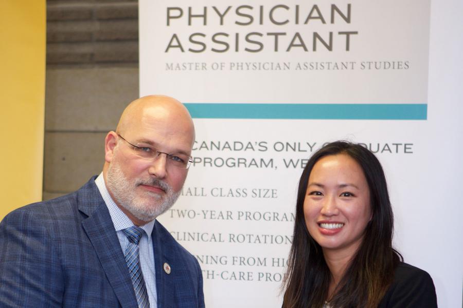 two people standing in front of a banner that shows the programs new name.