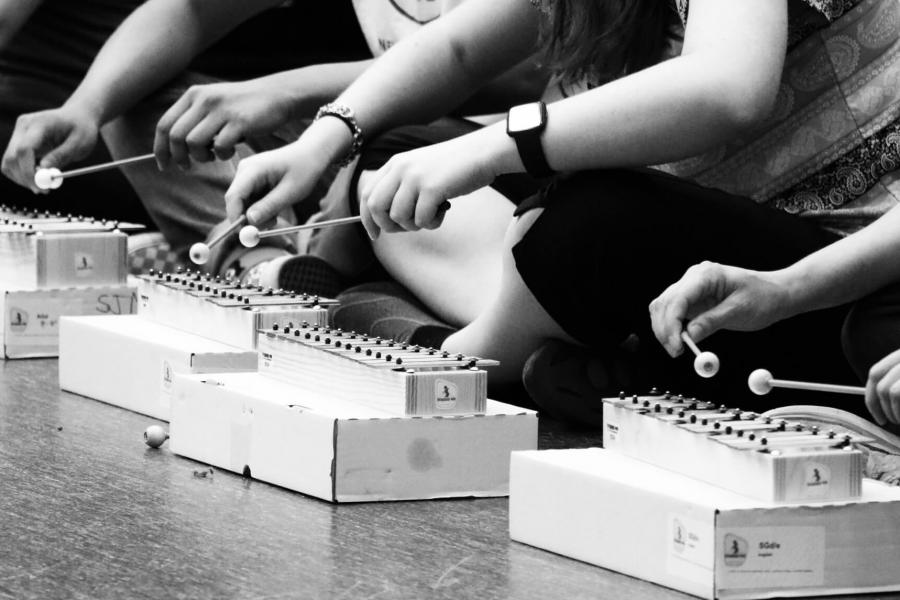 People seated on the floor playing xylophones. 