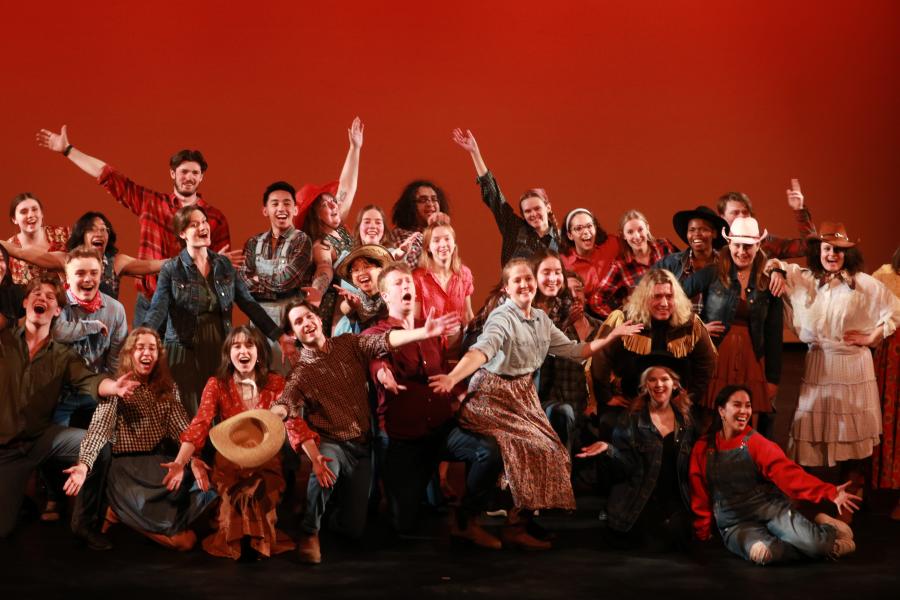 Performers dressed as cowboys pose with arms extended at the end of their performance of The Farmer and the Cowman, from the musical Oklahoma