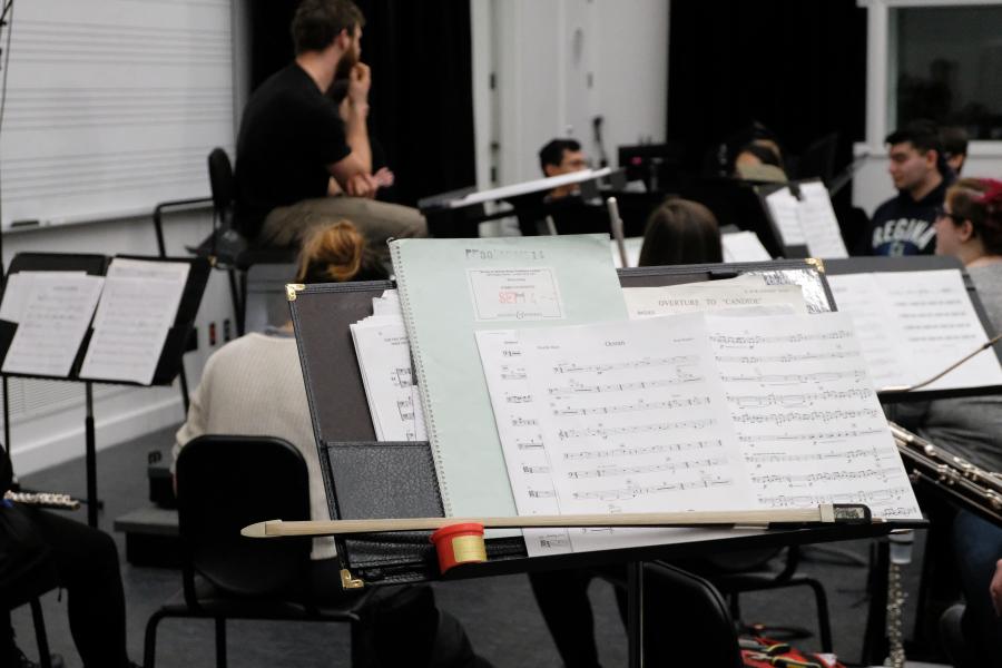 Sheet music and a drumstick on a music stand during an ensemble rehearsal.