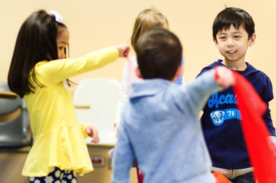 A group of young children stand together playing. 