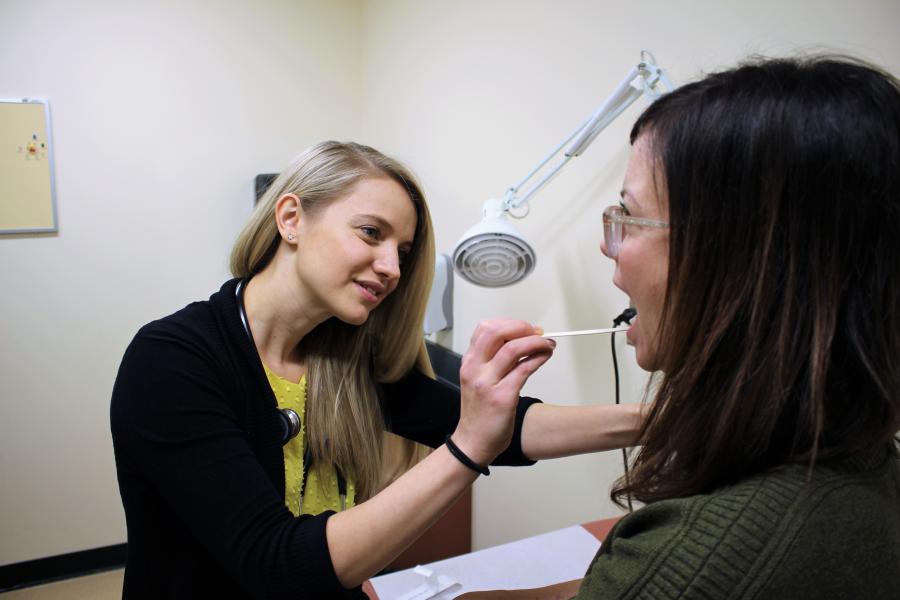 Nursing student doing an oral exam on a patient in clinic.