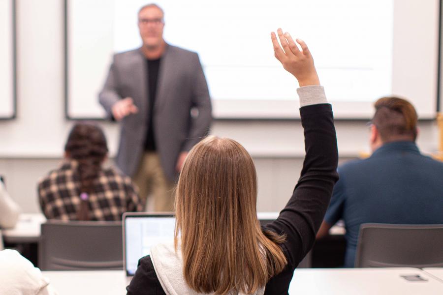A person raising their hand to ask a question in class.