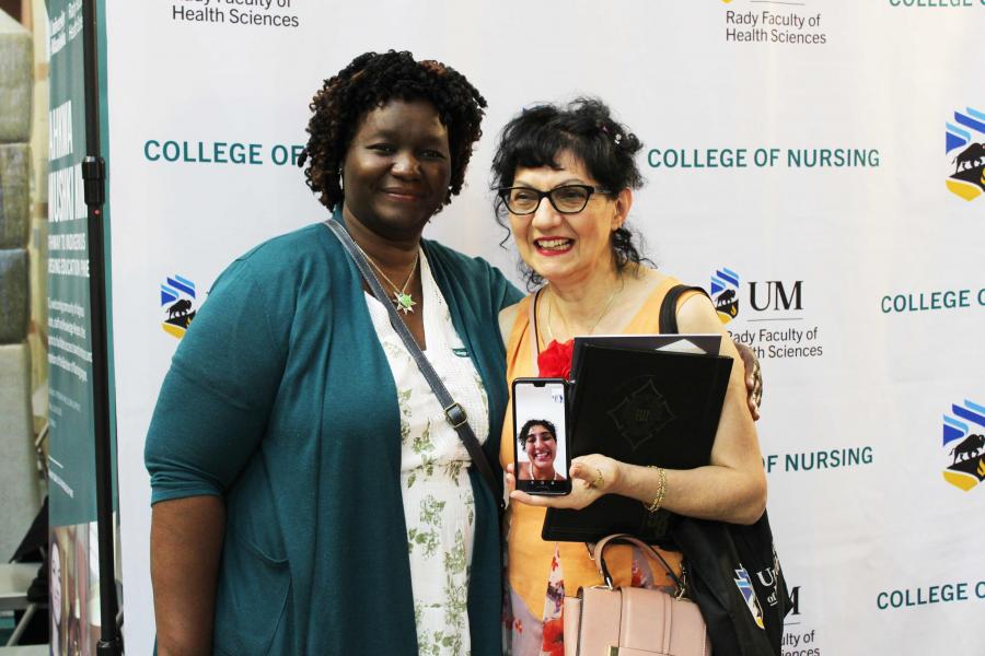 A pair of nursing alumna posing together at a homecoming event.