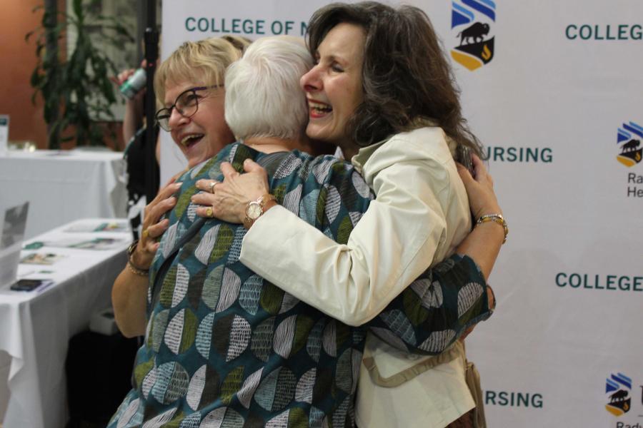Two nursing alumna hugging at a homecoming event.